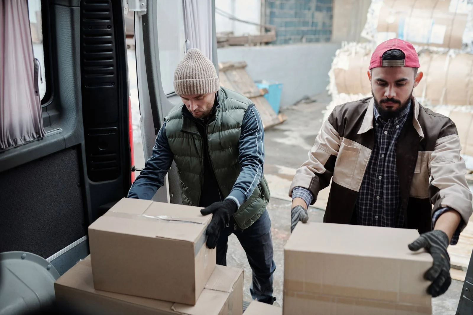 Dois trabalhadores carregando caixas em uma van de entrega