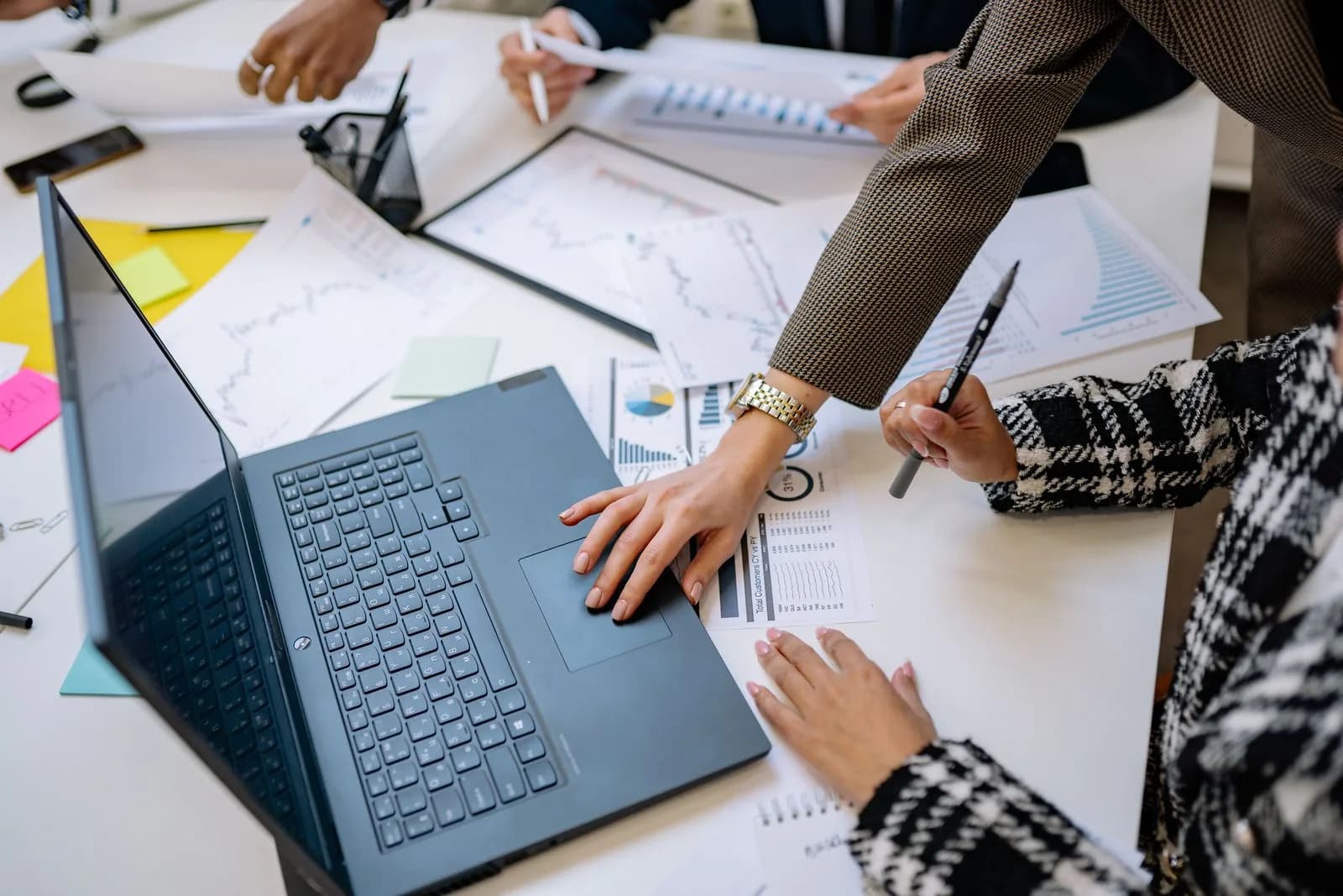 Equipe analisando gráficos e planilhas em volta de um notebook