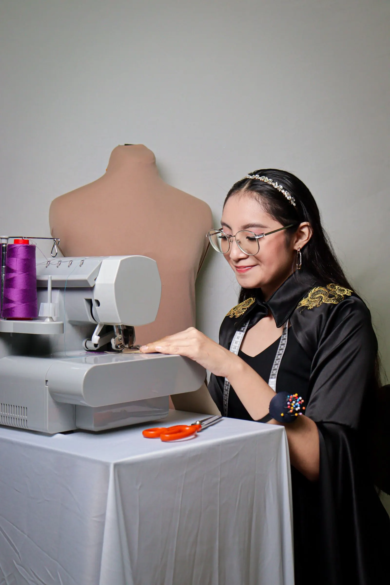 Costureira sorridente trabalhando na máquina de costura do seu ateliê