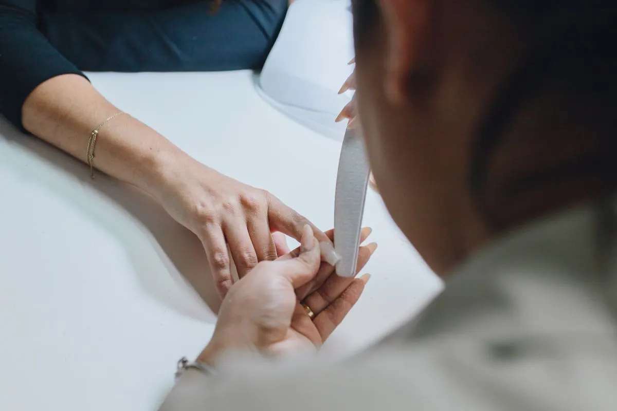 Manicure lixando as unhas de uma cliente